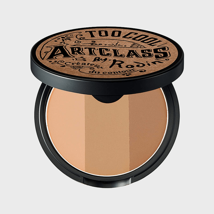 Compact makeup reveals three shades, housed in a round black container. The lid displays 