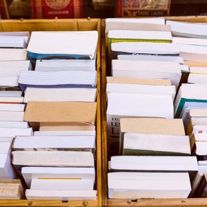 Books stacked vertically, showing spines, within wooden boxes on a shelf.