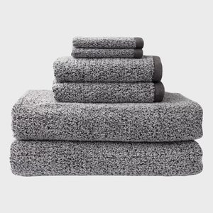 Gray towels stacked neatly, varying sizes, in a studio setting against a white background.