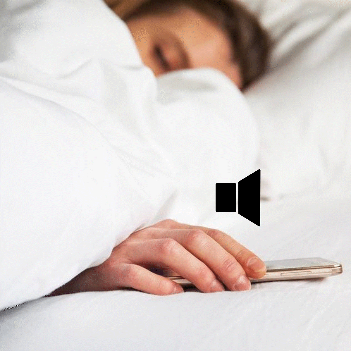 Hand rests on smartphone, laying on white bed, with speaker icon nearby.
