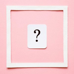 White card displays a question mark, centered within a rough white frame on a pink background.