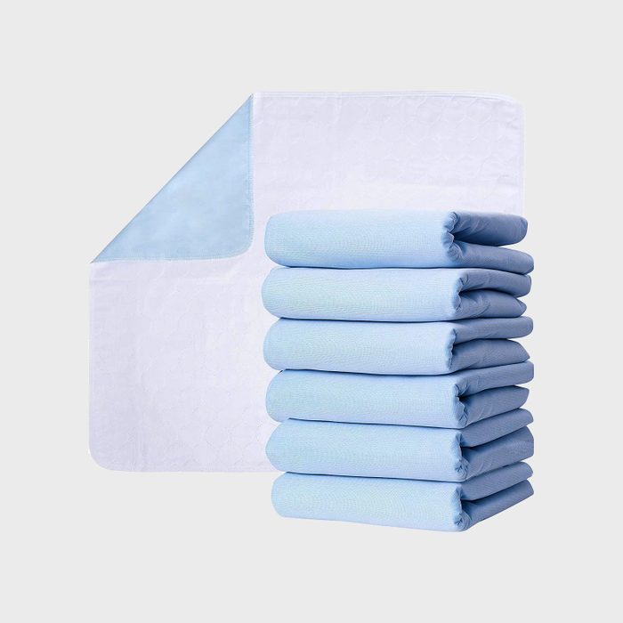 A stack of folded, light blue cloths beside an unfolded one, displayed against a plain background.