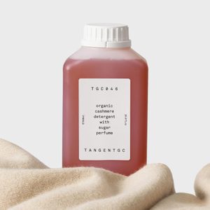 Bottle of organic cashmere detergent sits on fabric, labeled 