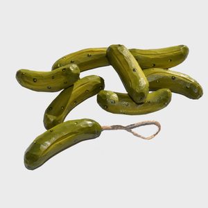 Several shiny green pickle-shaped objects are arranged with one attached to a looped string, set against a plain white background.