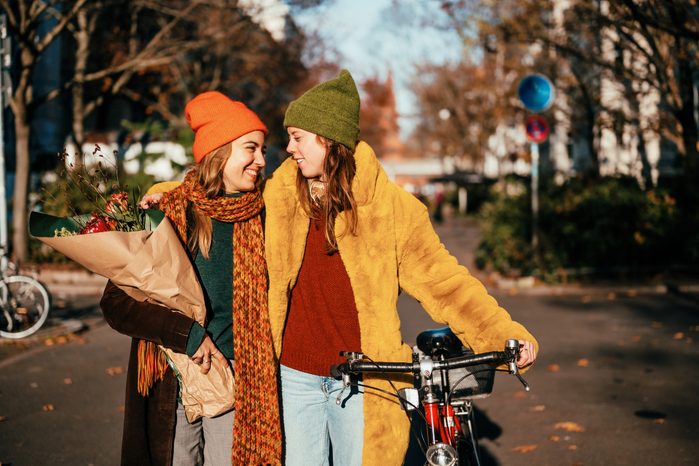 Two women on bikes on a sunny street