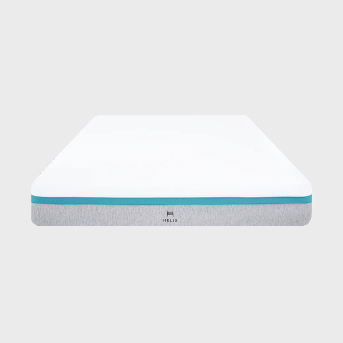 A mattress sits on a plain surface, featuring a white top, a blue stripe, and a gray base with 