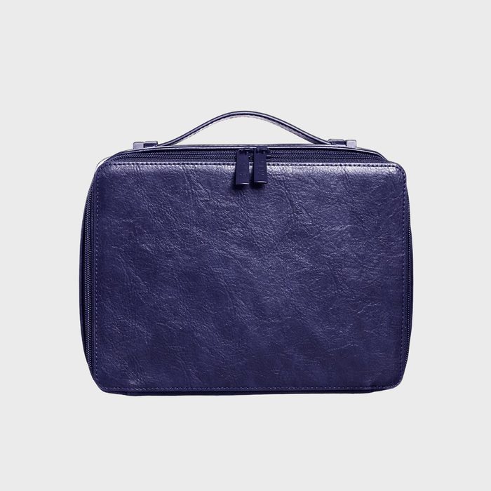 A navy leather bag sits upright, featuring a handle and dual zippers, placed against a plain gray background.