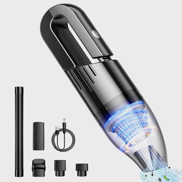 Handheld vacuum expels debris, surrounded by various attachments and a charging cable on a plain background.