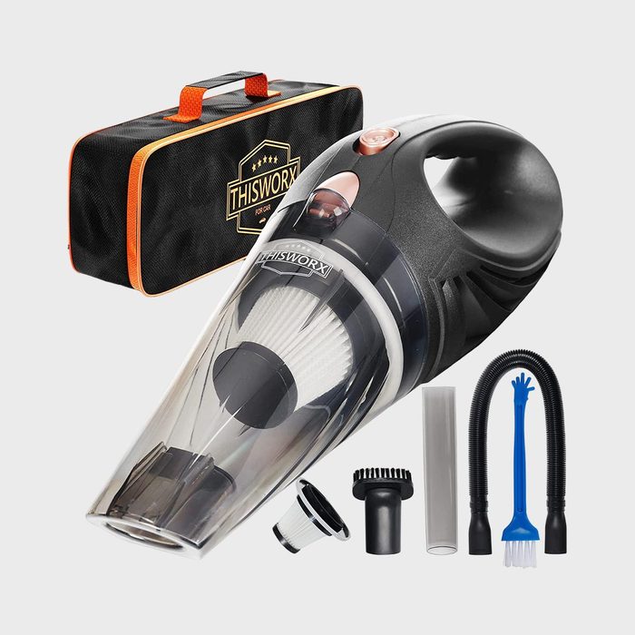 Portable vacuum with attachments sits next to a branded carrying bag, designed for car cleaning. Various nozzles and a filter are included.