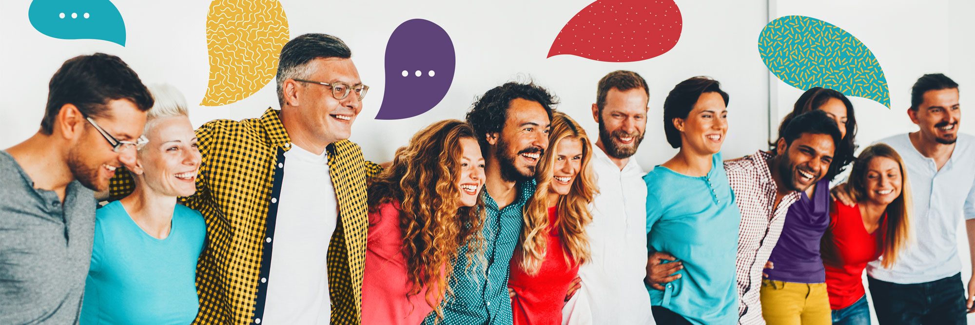 A group of diverse people stands closely, smiling and laughing, with colorful speech bubbles above them, in a bright, cheerful environment.