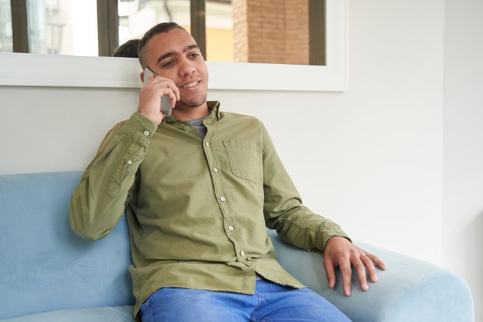 Cheerful man talking on mobile phone in waiting hall
