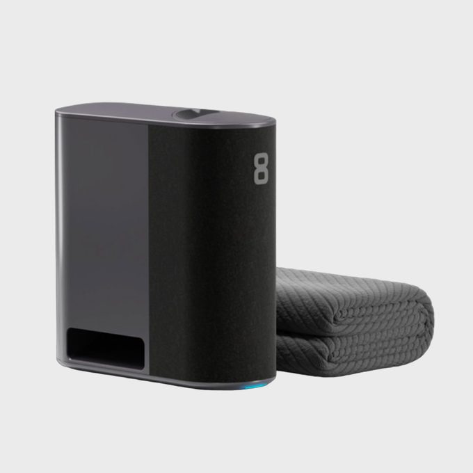 A rectangular black device sits beside a folded textured gray blanket on a light background. Number 