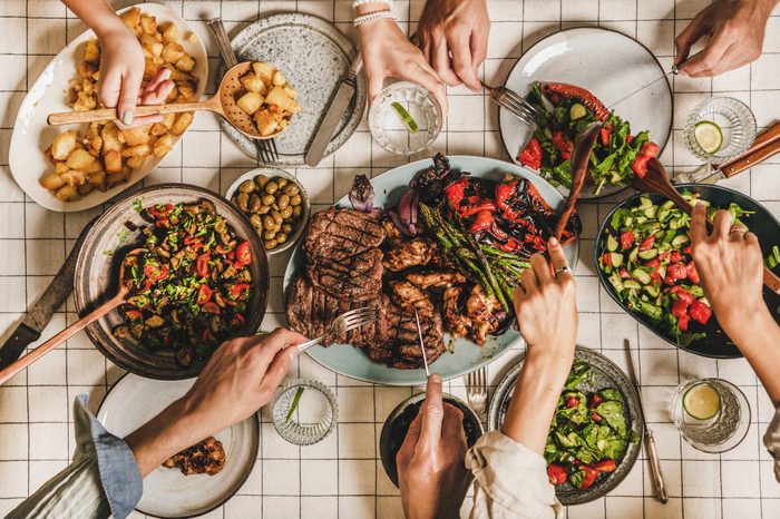 Flat-lay of people having barbeque party with meat and vegetables