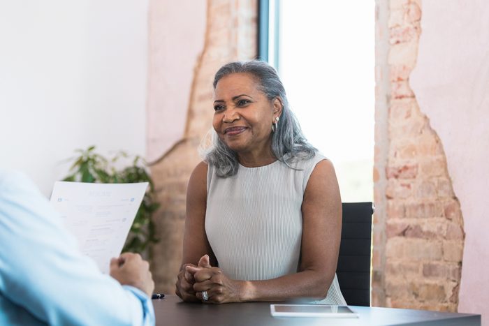 Nervous senior woman waits for male manager to review resume