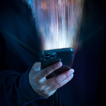 A smartphone emits glowing, vertical light beams upward in dimly lit surroundings.