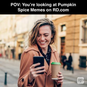 Woman smiles, holding a smartphone and cup, standing on a city street. Text: 