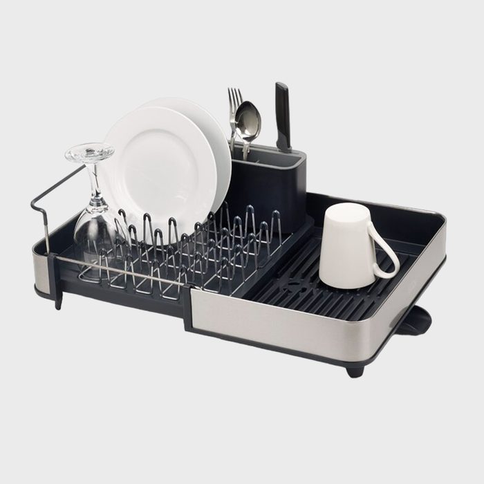 Dish rack holds plates, glass, utensils, and mug; placed on a kitchen countertop.