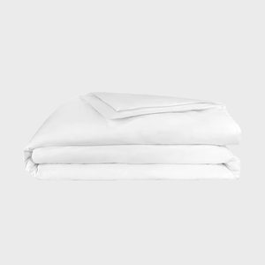A folded white duvet lies neatly on a plain, neutral background.
