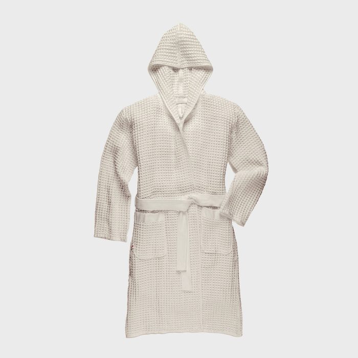 White waffle-textured robe rests against a plain background, featuring a hood and attached belt with pockets on the front.