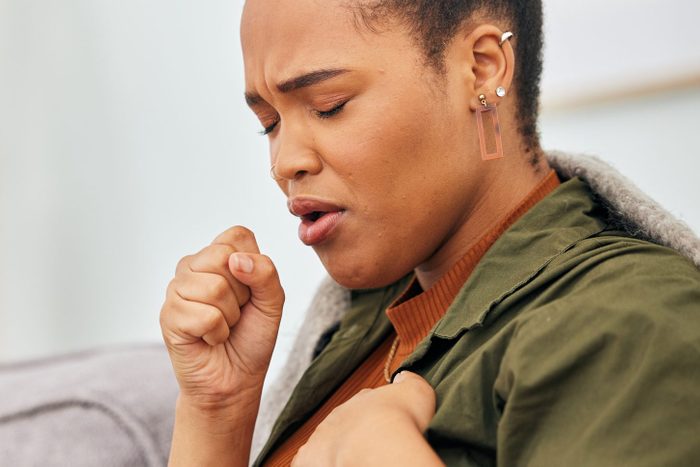 Sick, cough and woman in home with health problem of flu, cold or medical virus. Black female person, pain and coughing for asthma attack, tuberculosis and sore throat of allergy, lungs or pneumonia