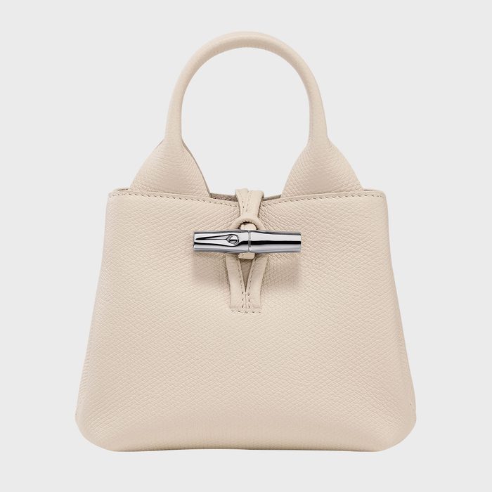 A beige handbag displays a silver clasp detail, set against a plain white background.