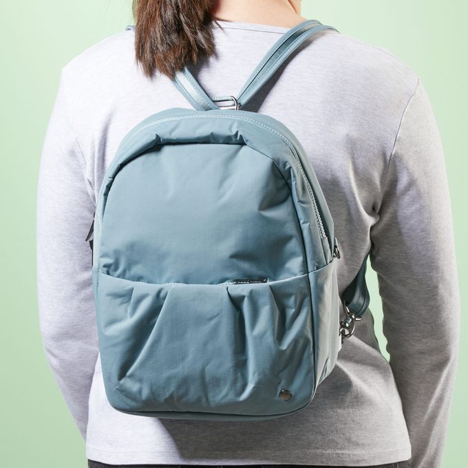 Backpack worn, resting on a person's back, against a light green background.