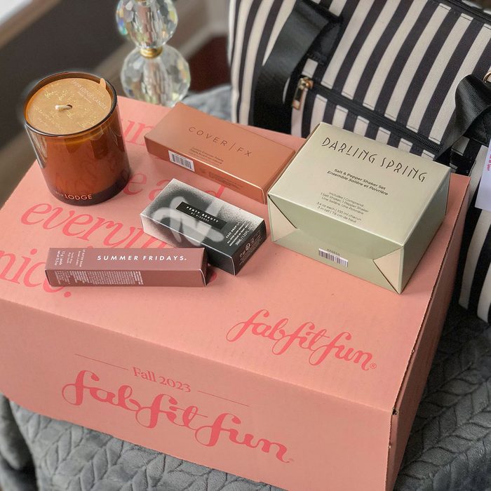Boxes and a candle are arranged on a pink 