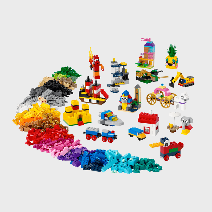 Colorful LEGO bricks are scattered, forming various small creations, including vehicles, buildings, and creatures, against a plain background.