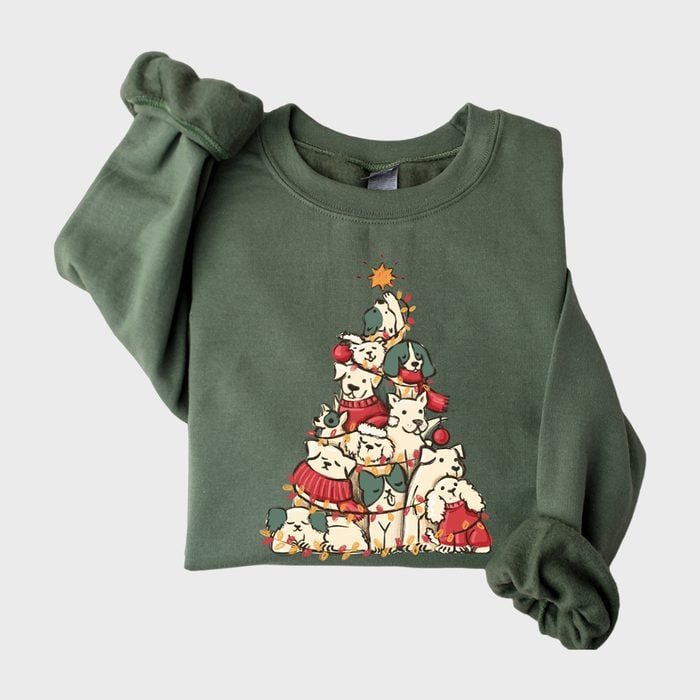 Green sweatshirt features cartoon animals stacked as a Christmas tree, wearing festive attire, with a star on top, creating a holiday theme.