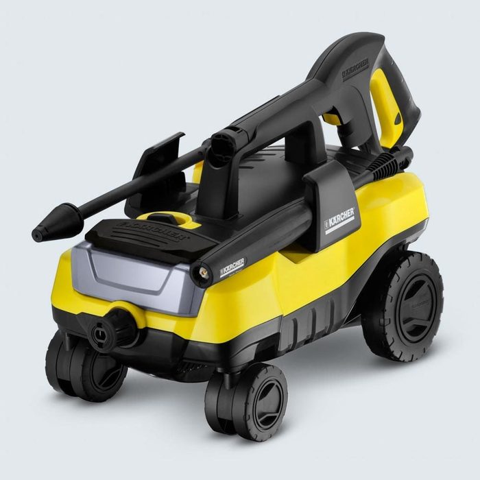 A yellow and black pressure washer rests on four wheels, featuring a spray nozzle and handle. Text on it reads 