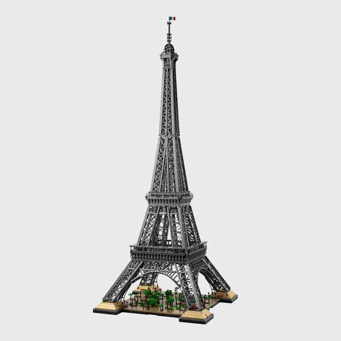LEGO Eiffel Tower model stands assembled, featuring intricate details and a small French flag, set against a plain white background.