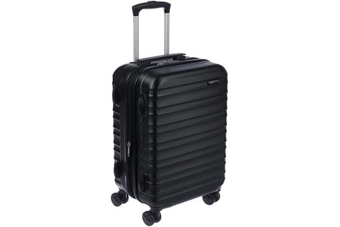 A black hard-shell suitcase stands upright, featuring four wheels and a telescopic handle, set against a plain white background.