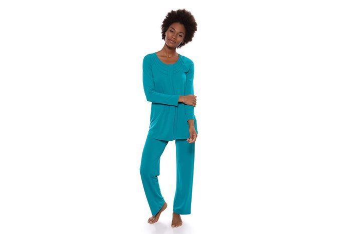 A person wearing teal loungewear stands casually, arms relaxed, against a plain white background.