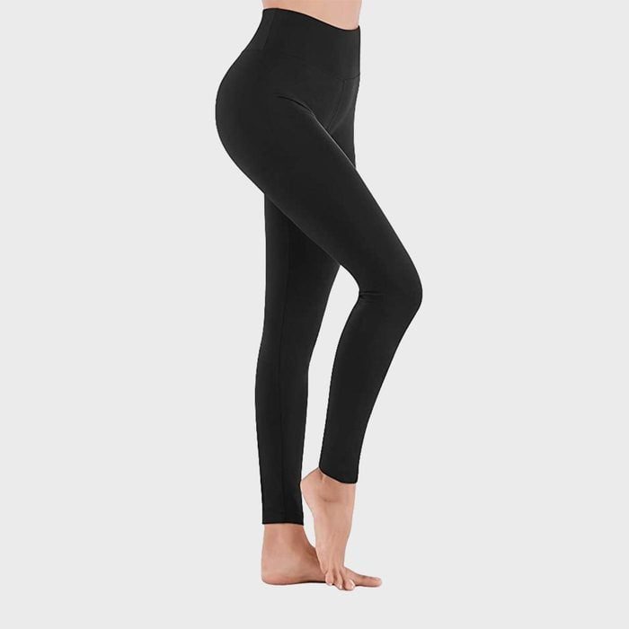 Person wearing black leggings stands on tiptoes against a plain gray background.