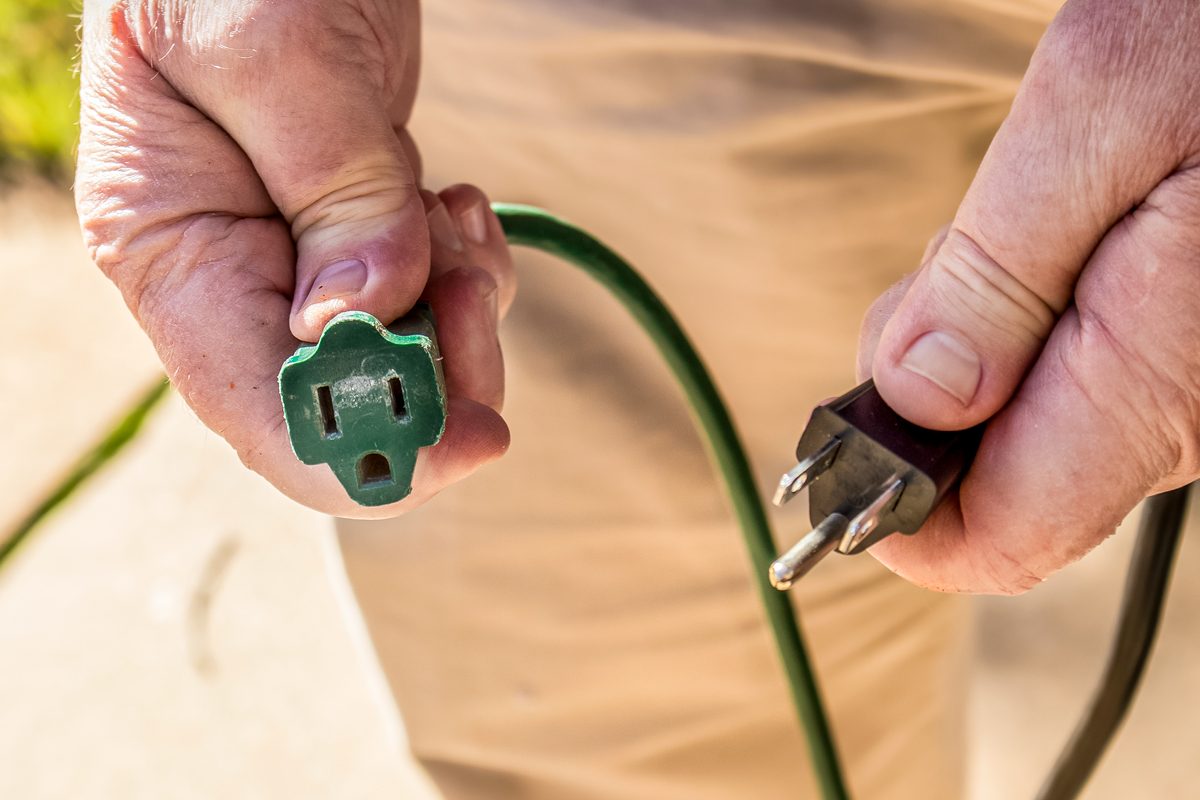 Electrical Cord And Green Extension Cord In Hands