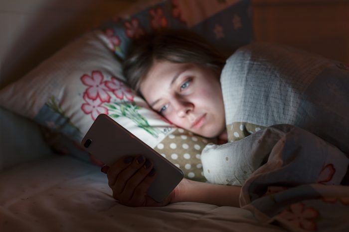 woman looking at phone in bed