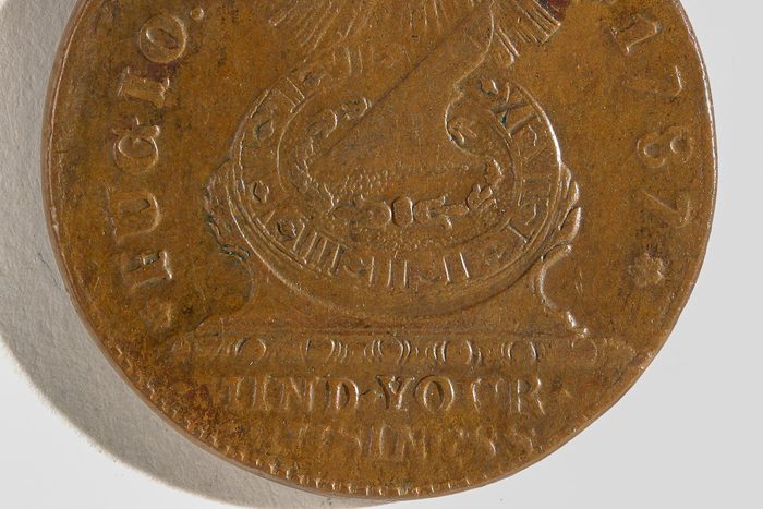 old coin with "mind your business" inscription
