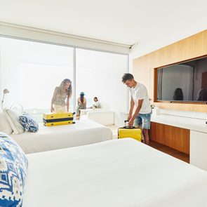 Wide Shot Of Siblings Preparing To Unpack Luggage In Hotel Room