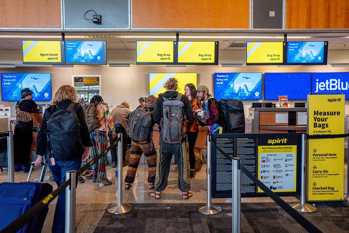 Customers wait in line to drop baggage off at a Spirit Airlines check-in counter at the Austin-Bergstrom International Airport 
