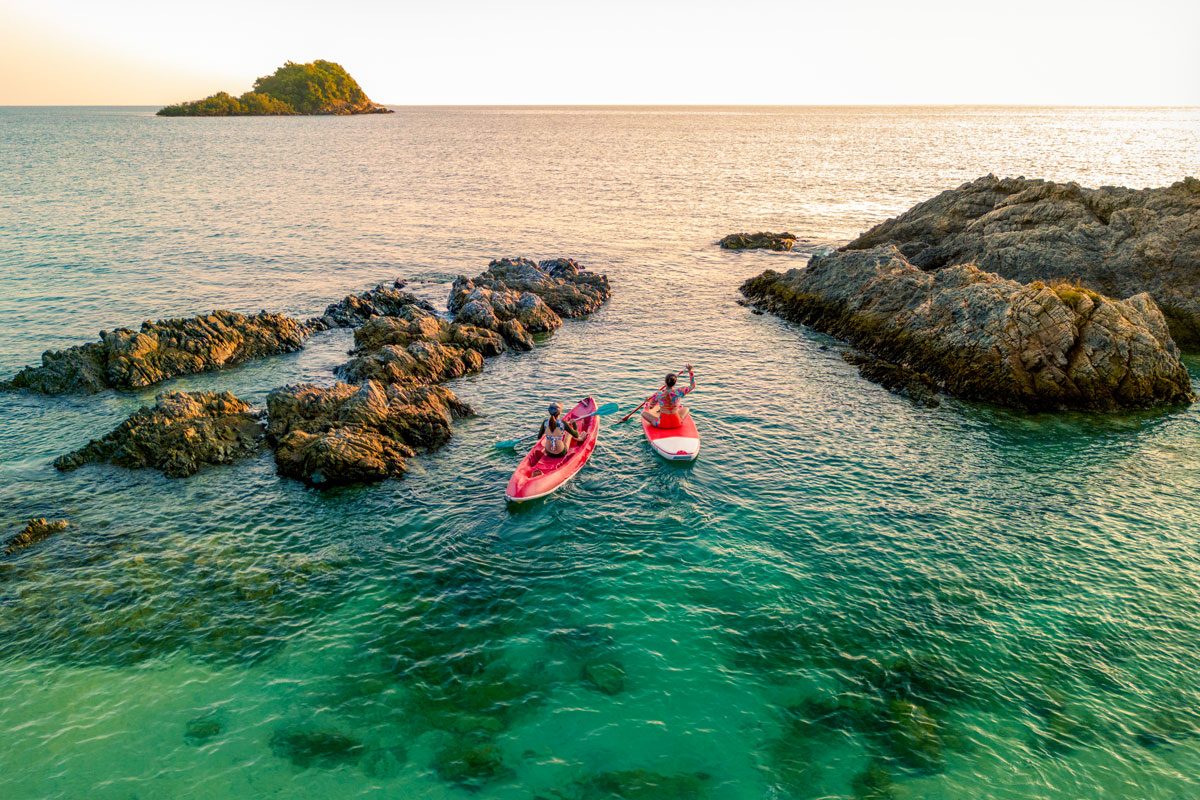 Two Women Kayaking In Green Ocean
